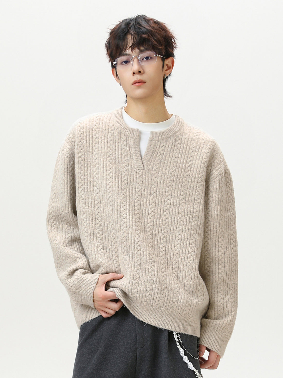 Model wearing men's cable knit v-neck sweater layered over a white collar shirt