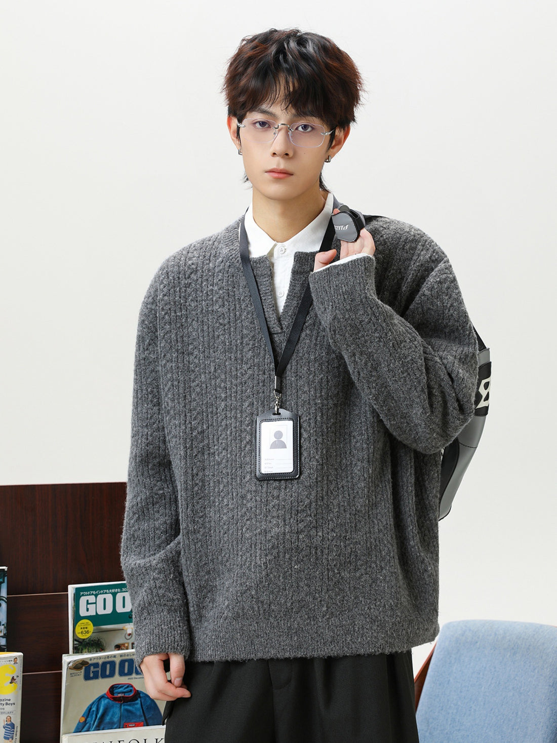 Model wearing men's cable knit v-neck sweater layered over a white collar shirt